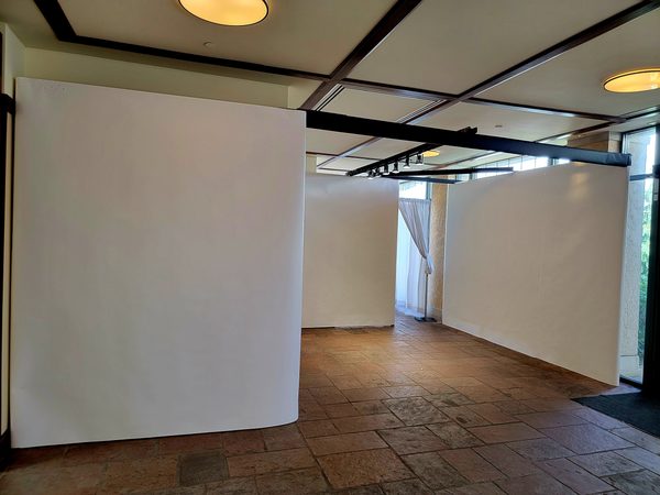 Tall white temporary walls with overhead track lighting on a stone tile floor, Omaha 2023